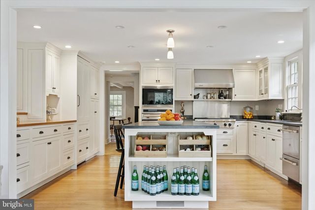 a kitchen with stainless steel appliances kitchen island granite countertop a stove a sink a refrigerator and white cabinets