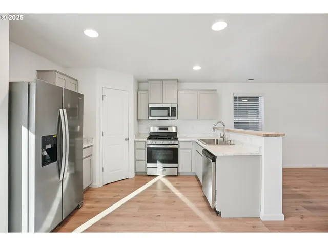 a kitchen with stainless steel appliances granite countertop a refrigerator a stove and a sink