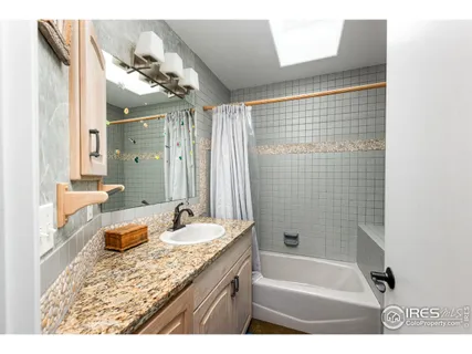 a bathroom with a granite countertop sink a mirror a bathtub and shower