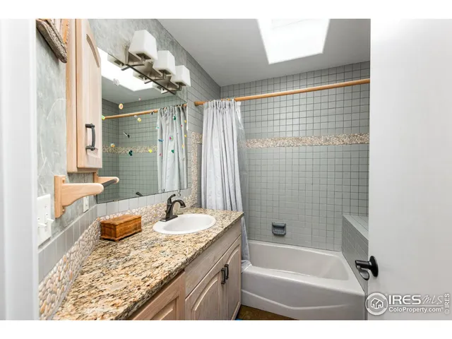 a bathroom with a granite countertop sink a mirror a bathtub and shower