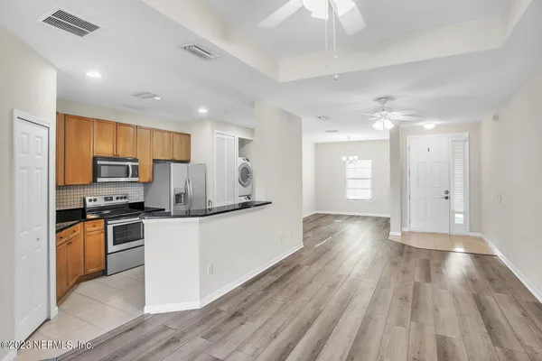 a kitchen with stainless steel appliances granite countertop a refrigerator a stove top oven a sink dishwasher and white cabinets with wooden floor
