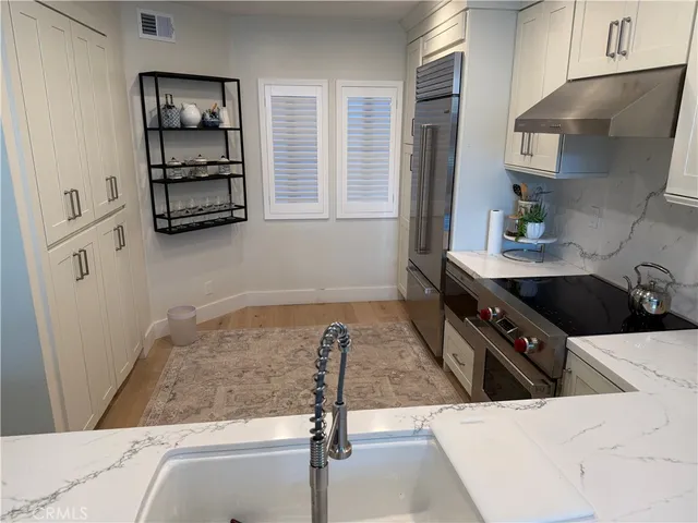 a living room with stainless steel appliances kitchen island granite countertop a refrigerator and a sink