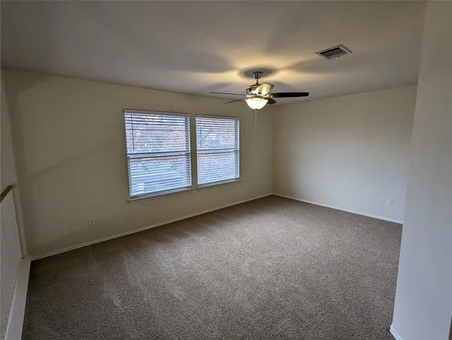 an empty room with windows and chandelier fan