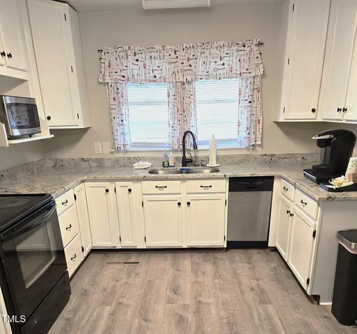 a kitchen with granite countertop white cabinets sink and stainless steel appliances