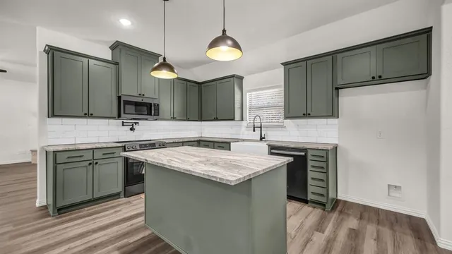 a kitchen with kitchen island granite countertop stainless steel appliances a sink stove and refrigerator