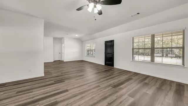 a view of an empty room with a window and wooden floor