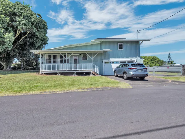 a front view of a house with a yard and potted plants