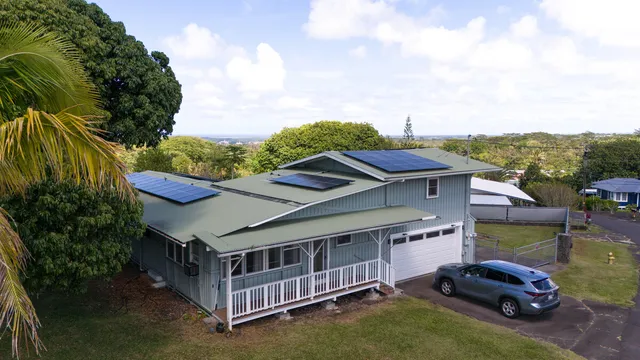 a white house that has a small yard and a large tree