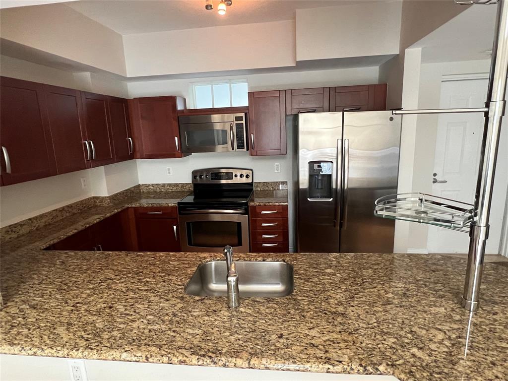 7275 Southwest 89th Street, Unit B520 Miami, FL 33156 - Photo 4 of 26 a kitchen with granite countertop a refrigerator and a stove top oven