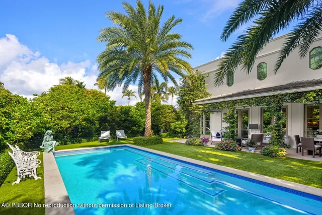 a view of a swimming pool with a lawn chairs and palm trees