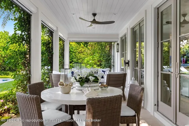a view of an outdoor dining space with a table chairs and a floor to ceiling window