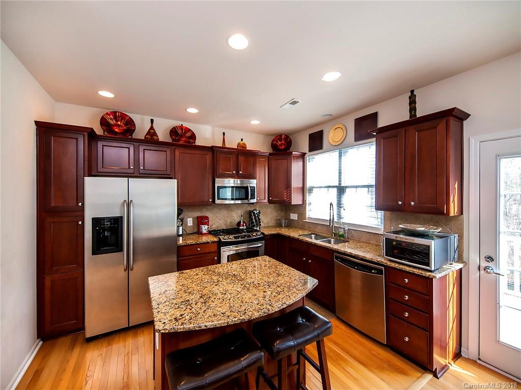 566 6th Baxter Crossing Fort Mill, SC 29708 - Photo 9 of 25 a kitchen with kitchen island granite countertop wooden cabinets a refrigerator a sink a stove and wooden floors