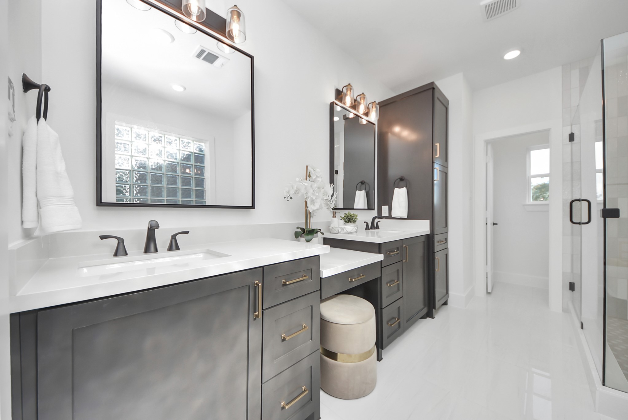 927 Fisher Street, Unit B Houston, TX 77018 - Photo 25 of 47 The modern bathroom impresses with dual vanities in dark cabinetry, white countertops, and stylish black fixtures. Elegant mirrors with overhead lighting, a large glass-enclosed shower, and abundant natural light create a bright, airy, and sophisticated space.