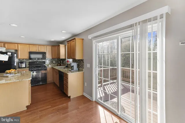 a kitchen with a refrigerator a stove top oven a sink dishwasher and a dining table with wooden floor