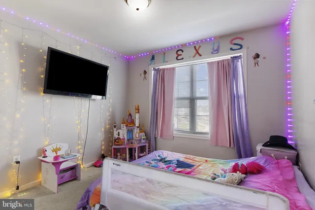 a bedroom with a bed a flat screen tv and a window