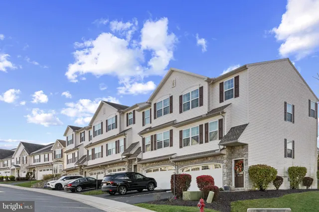 a front view of a building with lot of cars and trees