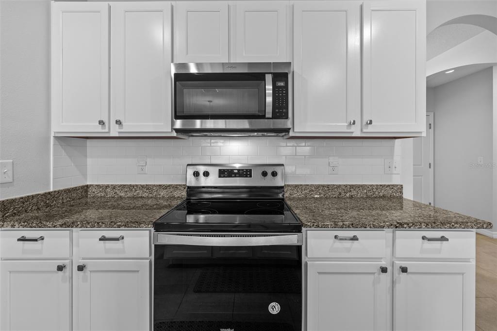 2721 Greenleaf Terrace Parrish, FL 34219 - Photo 26 of 65 a kitchen with stainless steel appliances granite countertop white cabinets and a stove top oven