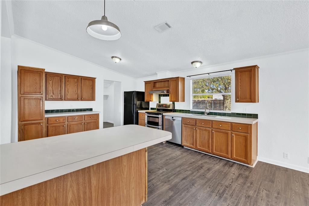 312 6th Street Joshua, TX 76058 - Photo 14 of 33 a kitchen with stainless steel appliances kitchen island granite countertop a stove a sink dishwasher and a refrigerator with wooden floor