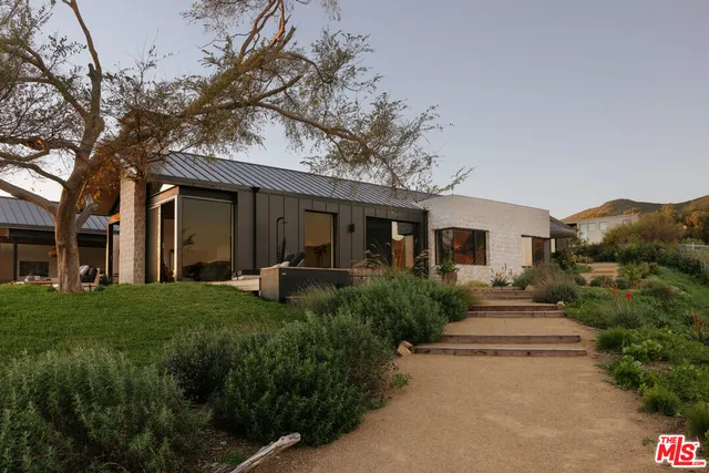 a front view of a house with a garden and plants