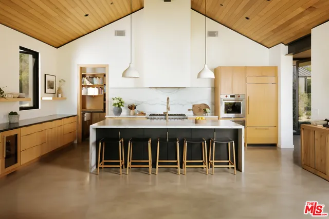 a dining room with stainless steel appliances kitchen island granite countertop a table chairs sink and cabinets