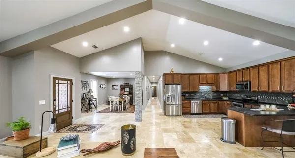 a living room with stainless steel appliances kitchen island a table and chairs in it