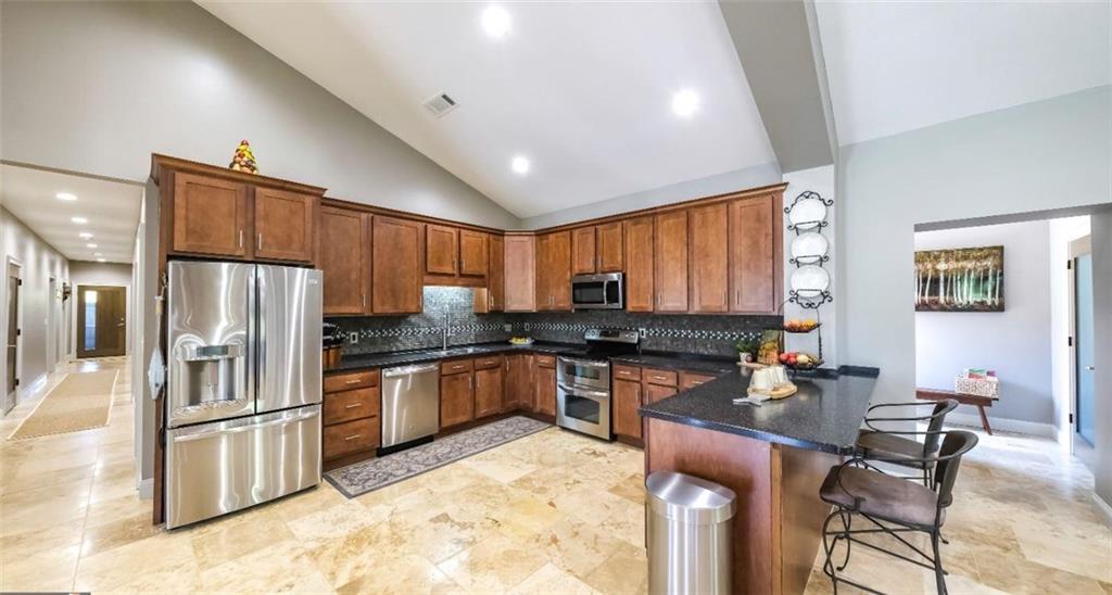 1600 Happy Hollow Road Roopville, GA 30170 - Photo 22 of 41 a kitchen with stainless steel appliances granite countertop a stove a refrigerator a sink a dining table and chairs with wooden floor