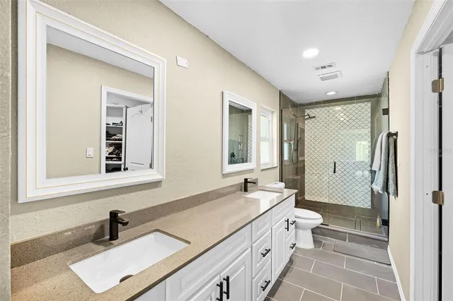 a bathroom with a double vanity sink a toilet and a mirror