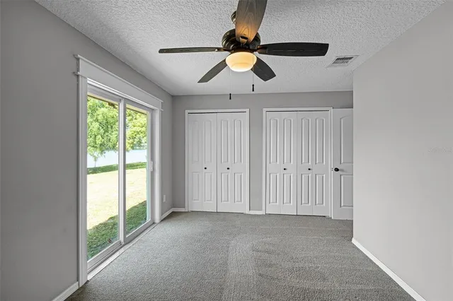a view of a livingroom with a chandelier fan and windows