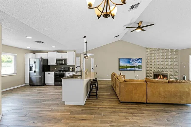 a living room with couches and kitchen view with wooden floor