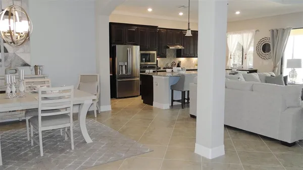 a living room with furniture kitchen view and a chandelier
