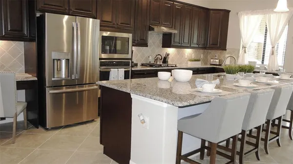 a kitchen with stainless steel appliances granite countertop a refrigerator a stove a sink and a microwave