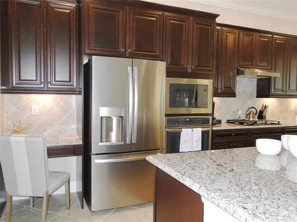 a kitchen with stainless steel appliances granite countertop a refrigerator a stove and a sink with wooden cabinets