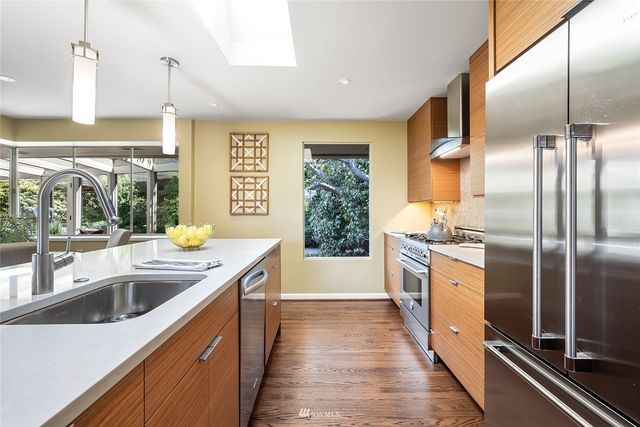 a kitchen with stainless steel appliances granite countertop a sink and a refrigerator