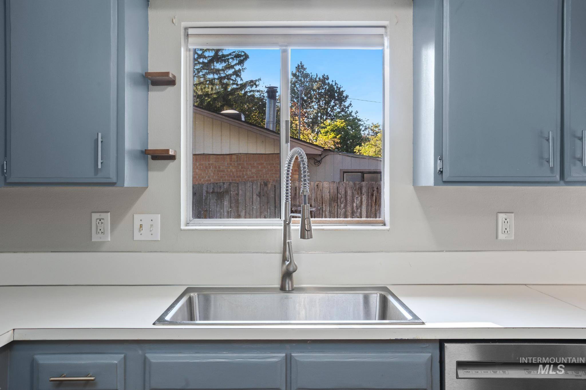 2037 South Curtis Road Boise, ID 83705 - Photo 15 of 32 Stainless steel undermount sink with a flexible gooseneck faucet, light-toned countertop, and blue cabinetry with brushed nickel hardware