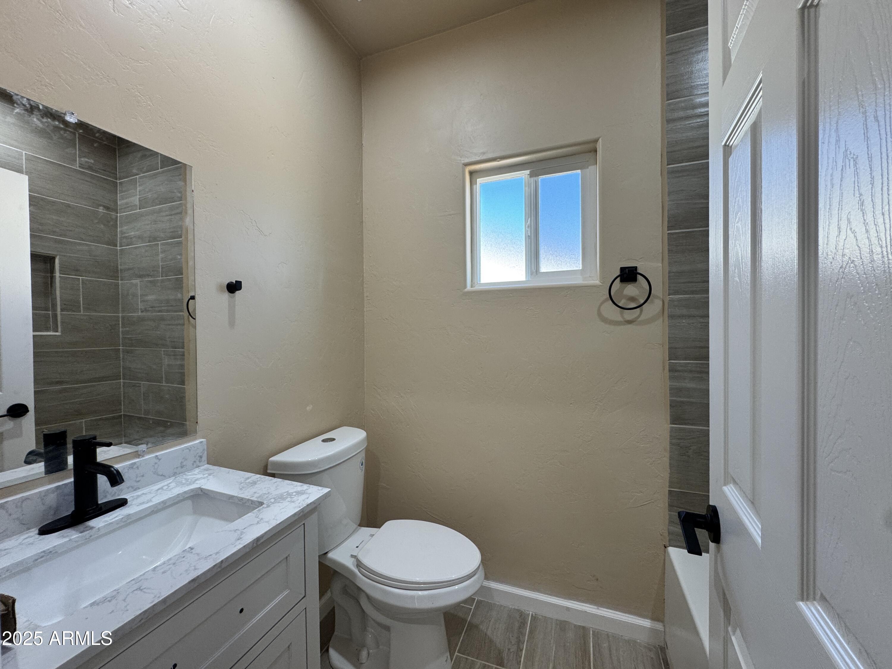 1457 East 23rd Street Douglas, AZ 85607 - Photo 6 of 23 a bathroom with a granite countertop toilet a sink a mirror and shower