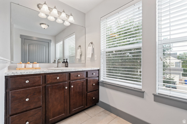 7822 North Copperbend Road Eagle Mountain, UT 84005 - Photo 33 of 46 Dual windows with horizontal blinds, a wood-finish vanity with multiple storage drawers and cabinets, a single basin sink, a large wall-mounted mirror, and a vanity light fixture with multiple shades