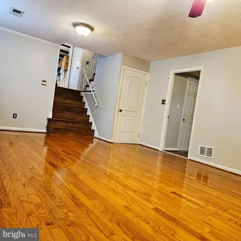 a view of an empty room with wooden floor and stairs
