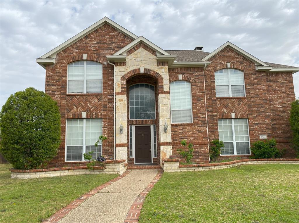 View of front of property with a shingled roof, stone siding, a front lawn, and brick siding