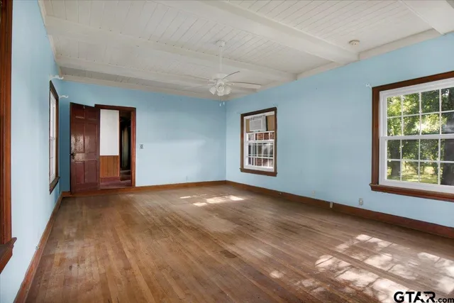 a view of an empty room with window and wooden floor