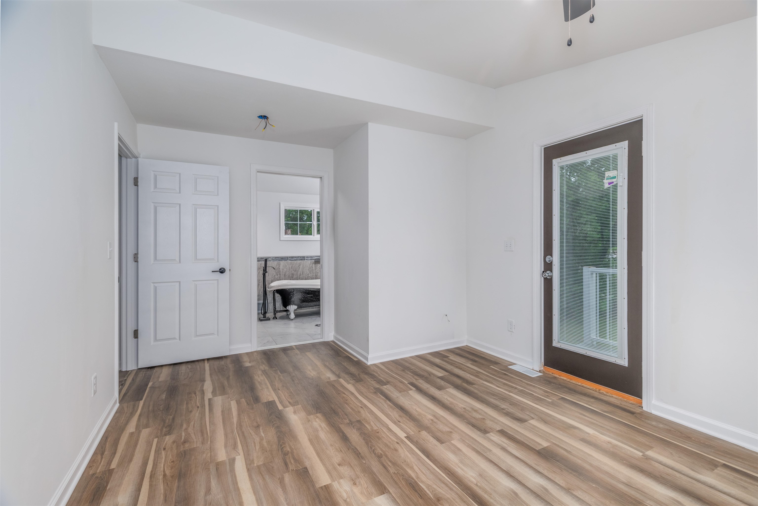 27 Astor Road Babbitt, MN 55706 - Photo 15 of 22 Primary bedroom looking at ensuite claw foot tub with finished floors and a ceiling fan