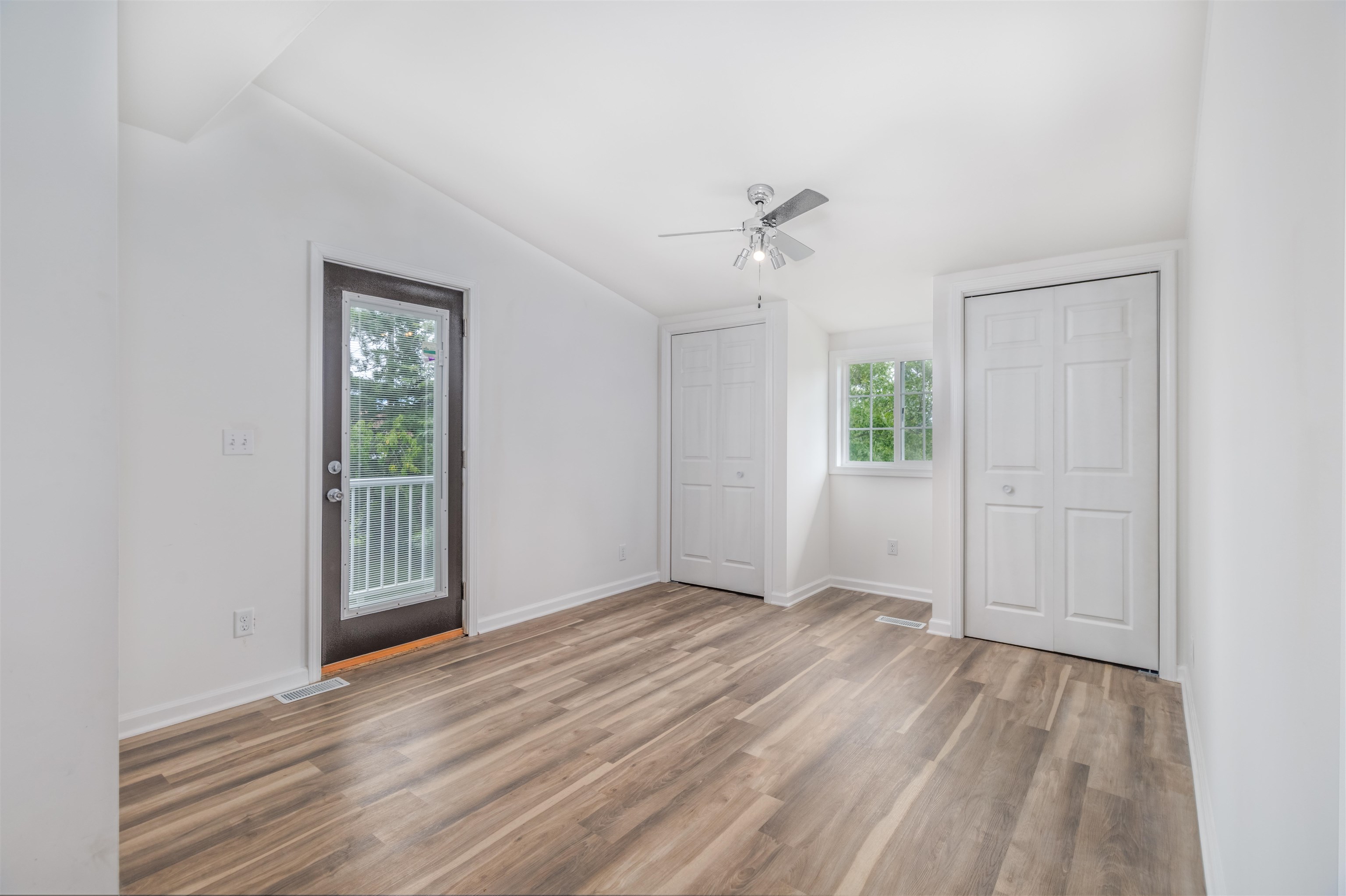 27 Astor Road Babbitt, MN 55706 - Photo 16 of 22 Primary Bedroom featuring two closets, vaulted ceiling, private balcony access to outside, light wood-style flooring, and a ceiling fan