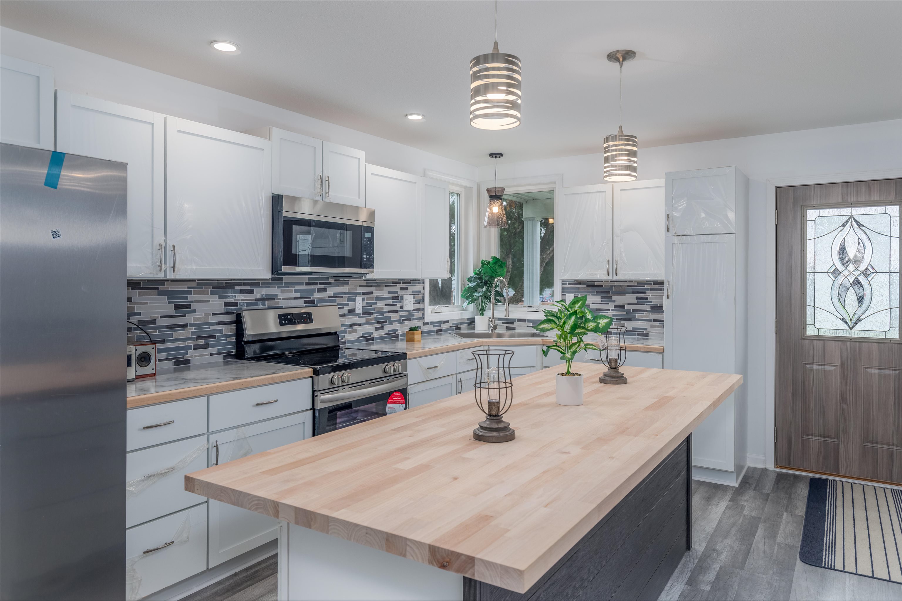 27 Astor Road Babbitt, MN 55706 - Photo 4 of 22 Kitchen with stainless steel appliances, decorative backsplash, pendant lighting, breakfast bar with butcher block top, new flooring, and recessed lighting