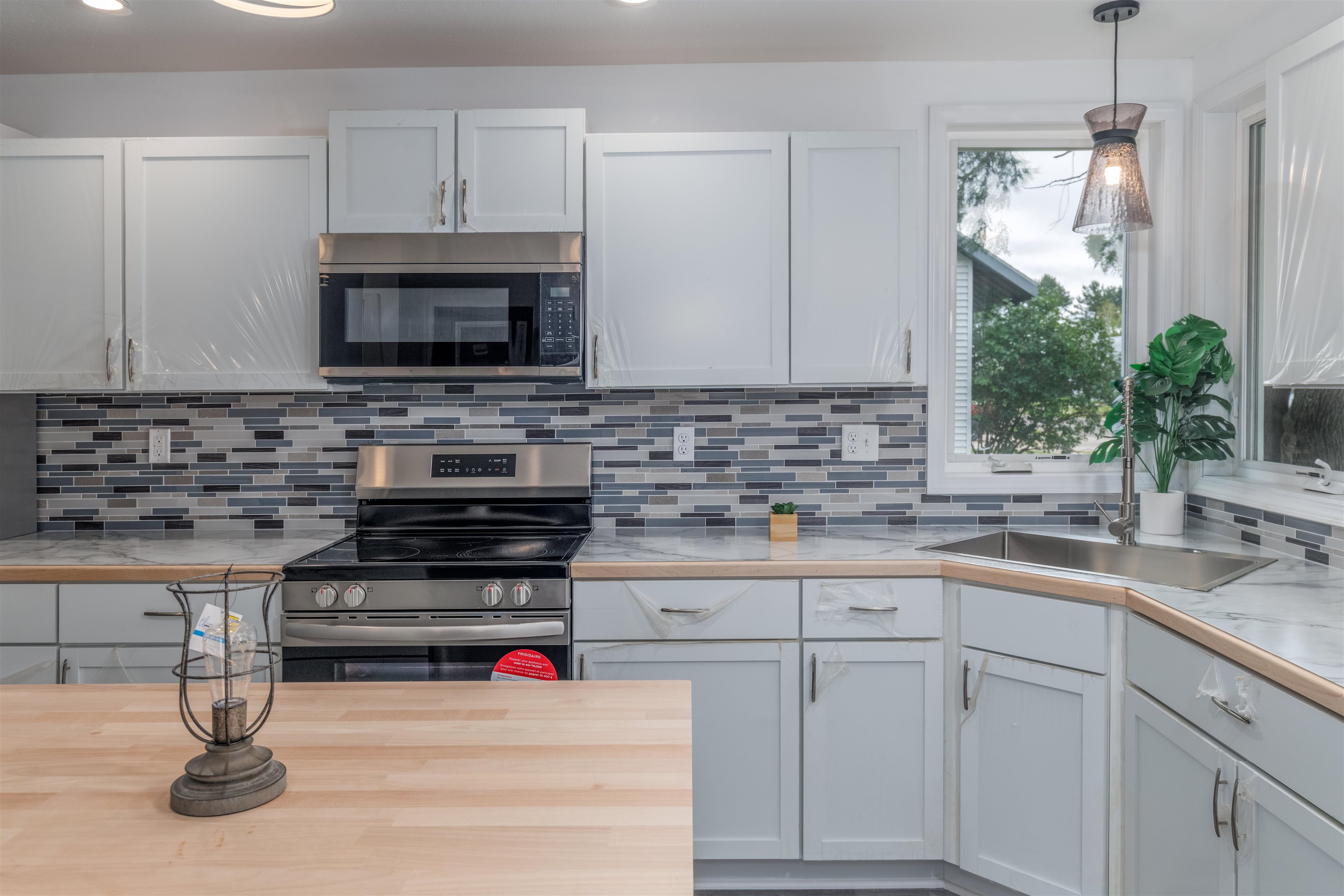 27 Astor Road Babbitt, MN 55706 - Photo 5 of 22 Kitchen featuring hanging light fixtures, stainless steel appliances, tasteful backsplash, white cabinets, and recessed lighting