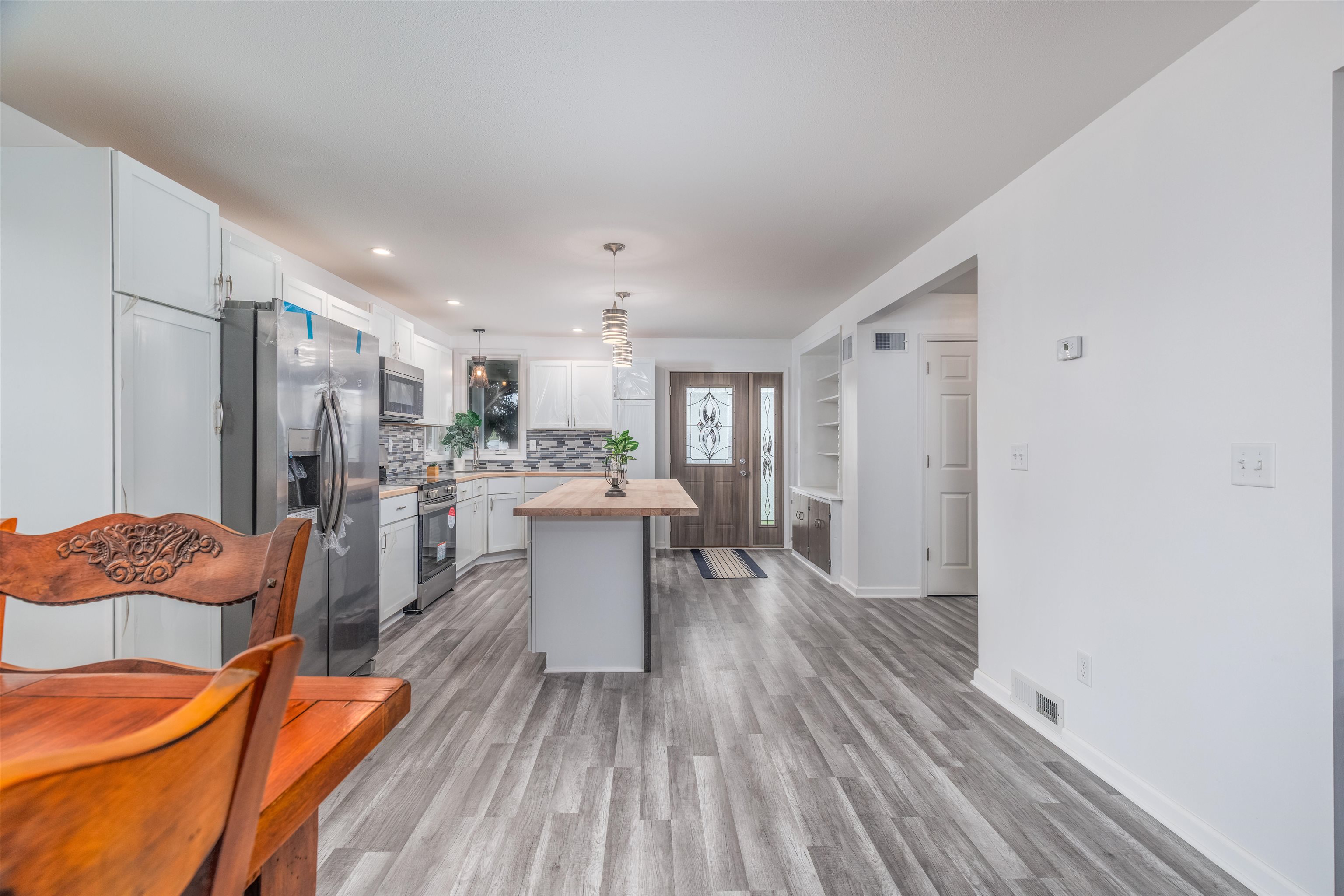 27 Astor Road Babbitt, MN 55706 - Photo 8 of 22 Dining to Kitchen view Kitchen with wooden counters, a kitchen island, stainless steel appliances, hanging light fixtures, and white cabinets