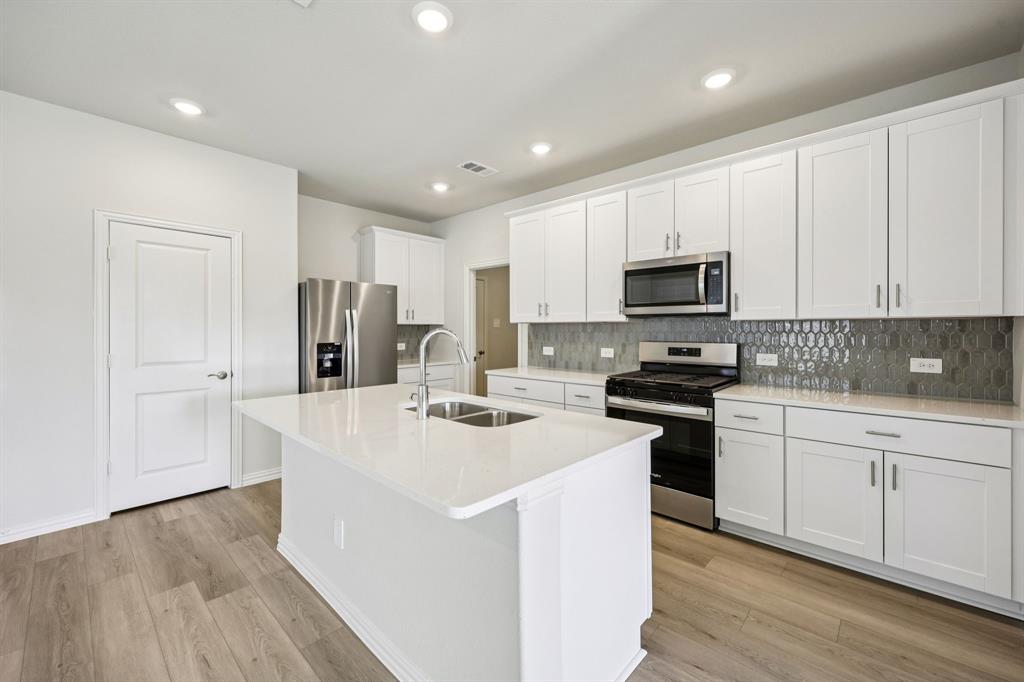 a kitchen with stainless steel appliances a refrigerator stove microwave and white cabinets