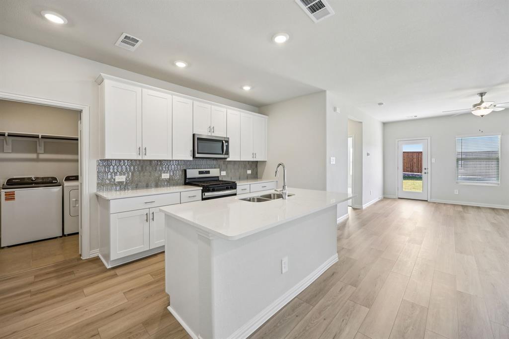 1737 Arches Road Anna, TX 75409 - Photo 4 of 38 a kitchen with a sink a stove top oven a refrigerator and white cabinets with wooden floor