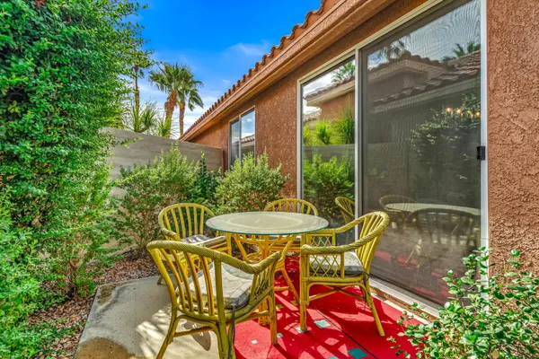 a patio with table and chairs and potted plants