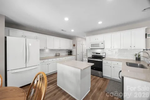 a kitchen with granite countertop white cabinets and white appliances