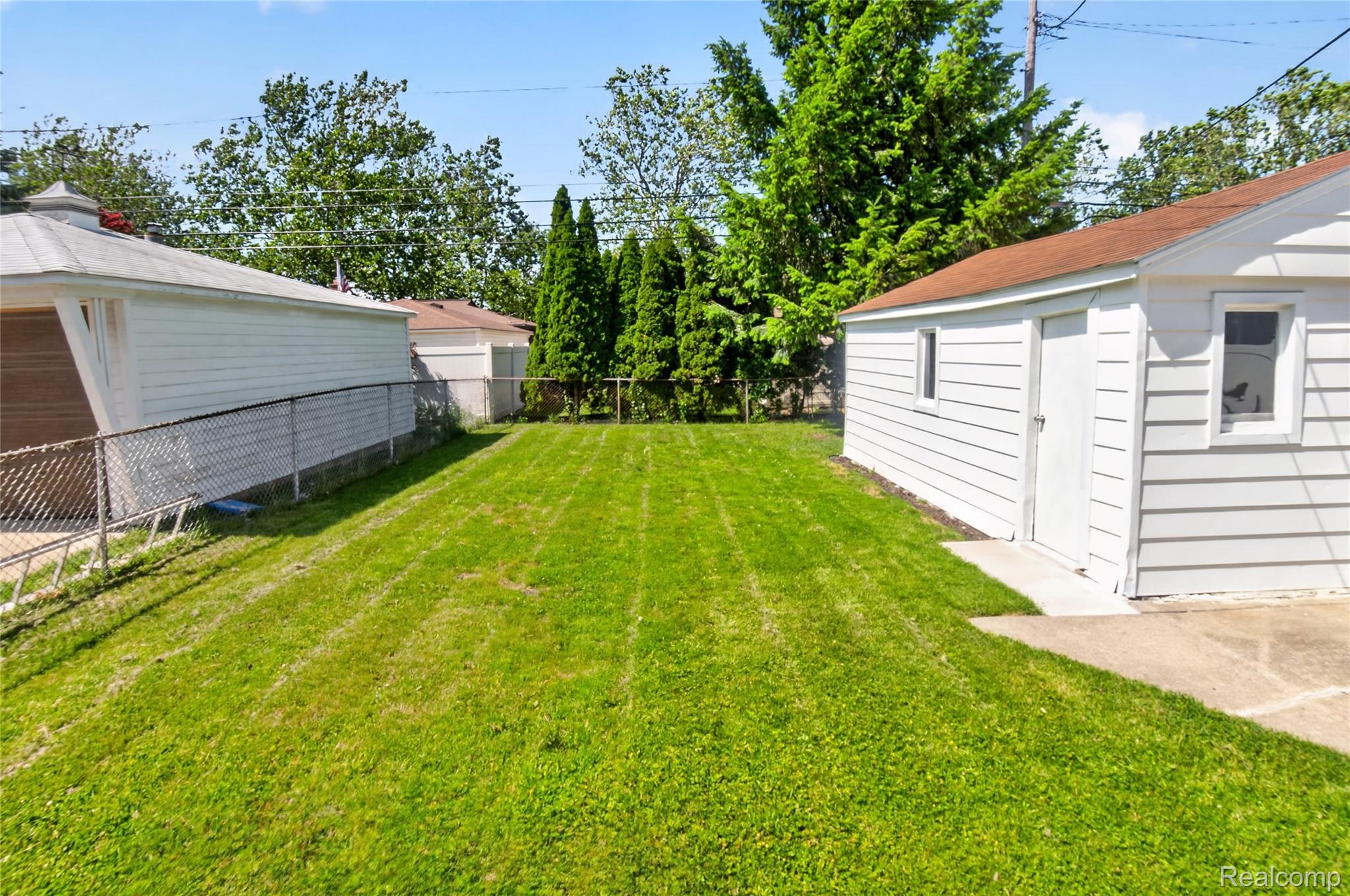 12972 Callender Street Southgate, MI 48195 - Photo 39 of 40 Expansive backyard featuring a manicured lawn, chain link fencing, mature perimeter trees, and concrete patio space