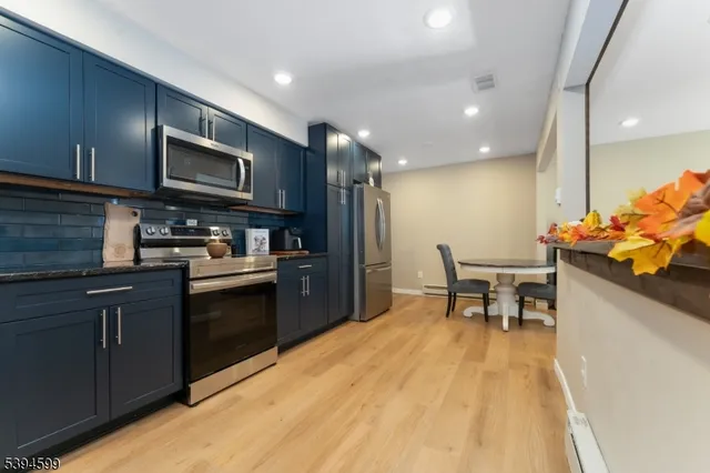 a kitchen with stainless steel appliances kitchen island granite countertop a refrigerator and a stove top oven